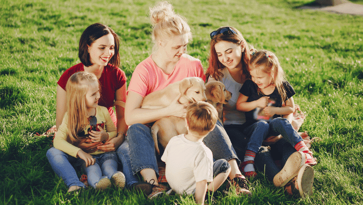 three women are playing with puppy with their three kids